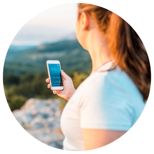 Woman checking CGM numbers on her smartphone app while outside.